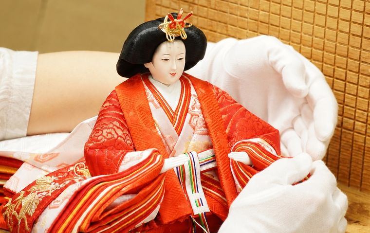 白手袋で雛人形の衣装を整える伝統工芸士の手元